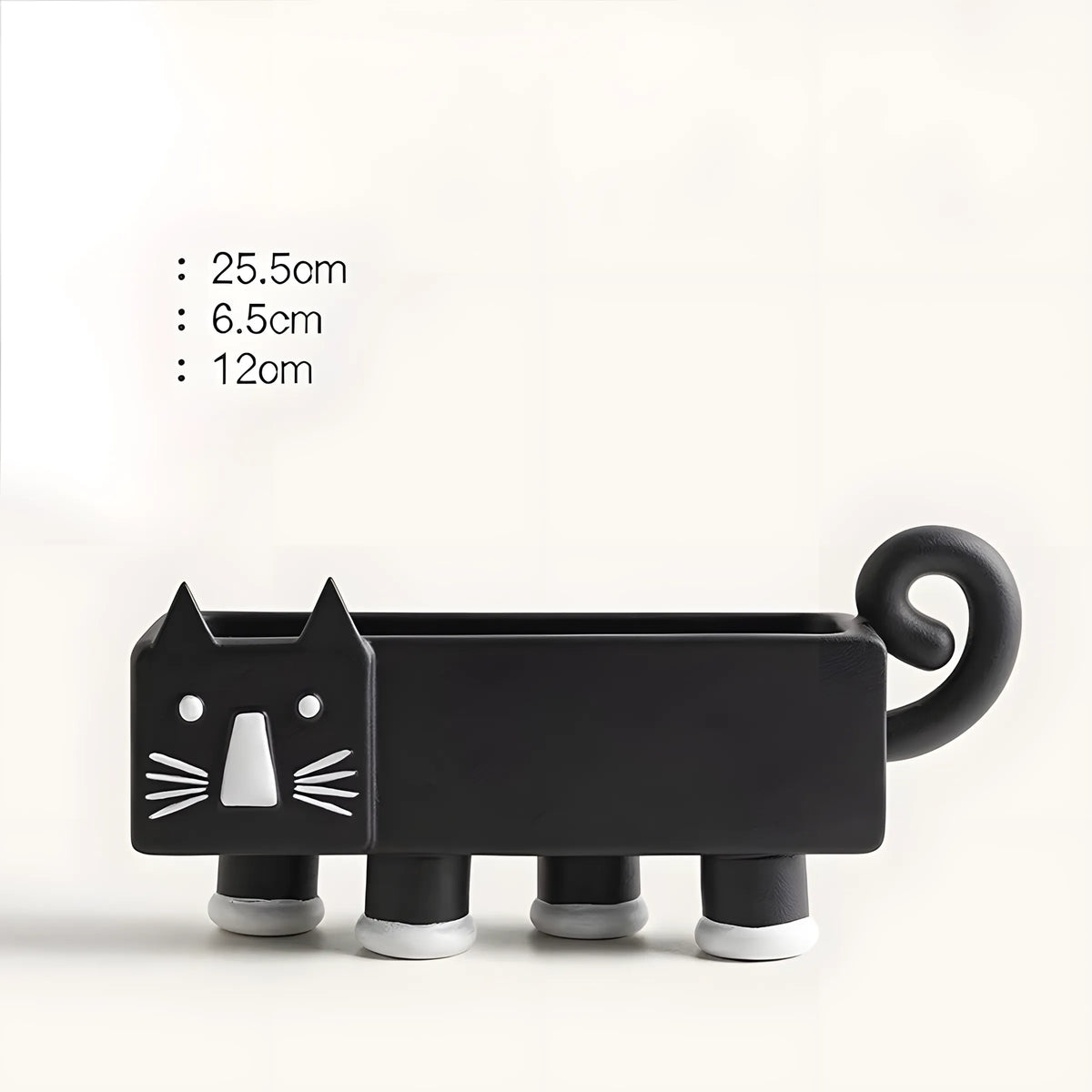 A black cat-shaped planter with white facial details and cylindrical legs, shown on a light neutral background with printed dimensions on the left: 25.5cm, 6.