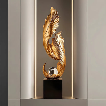 Decorative gold sculpture on a black base against a neutral wall.