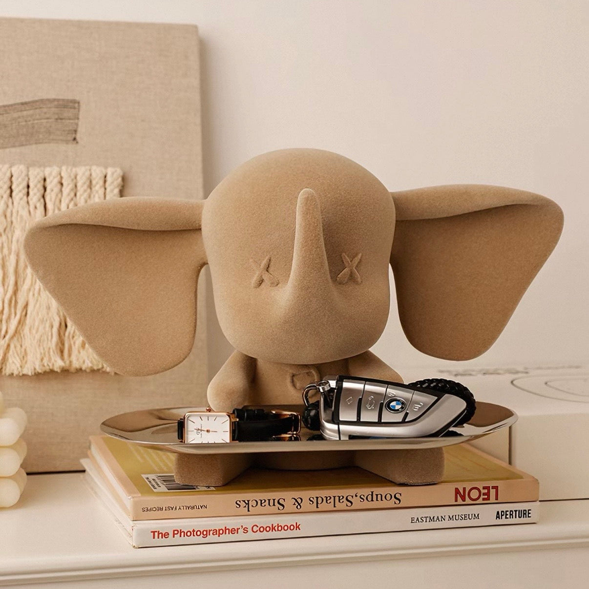 Beige elephant-shaped decorative item on a stack of books with a blurred background