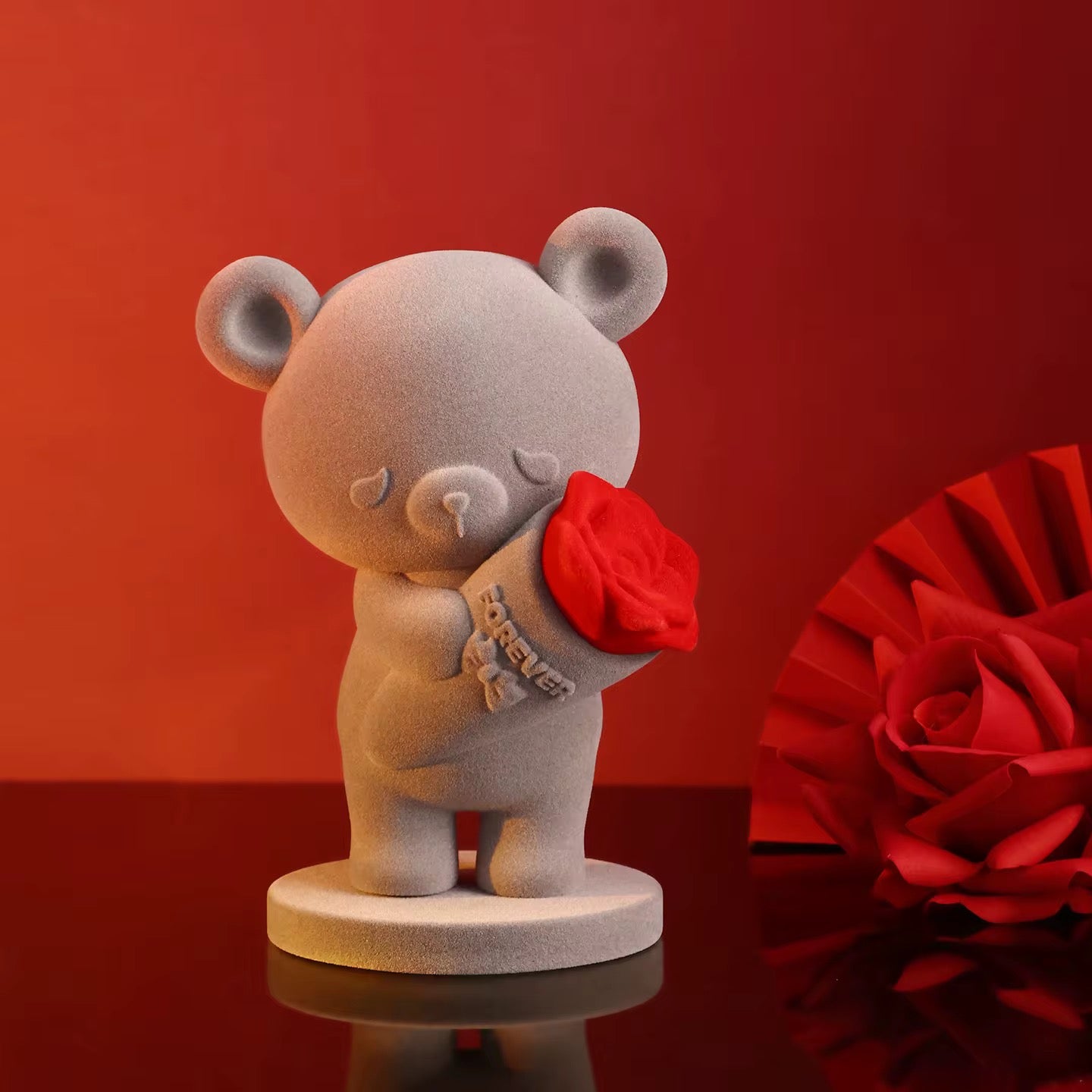 Ceramic bear figurine holding a red rose against a red background