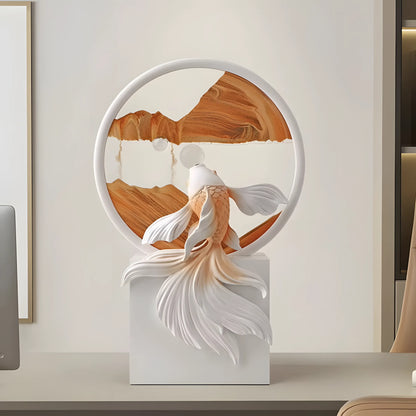 A decorative sculpture of a goldfish in front of a circular wooden and white wall art piece, mounted on a white pedestal in a modern interior setting.