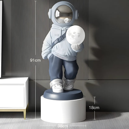 A cartoon astronaut figurine wearing a light blue hoodie, dark blue pants, and white sneakers, holding a glowing moon lamp. The image includes dimension lines showing the figurine's height of 91cm, the moon lamp's diameter of 18cm, and the pedestal's diameter of 38cm.
