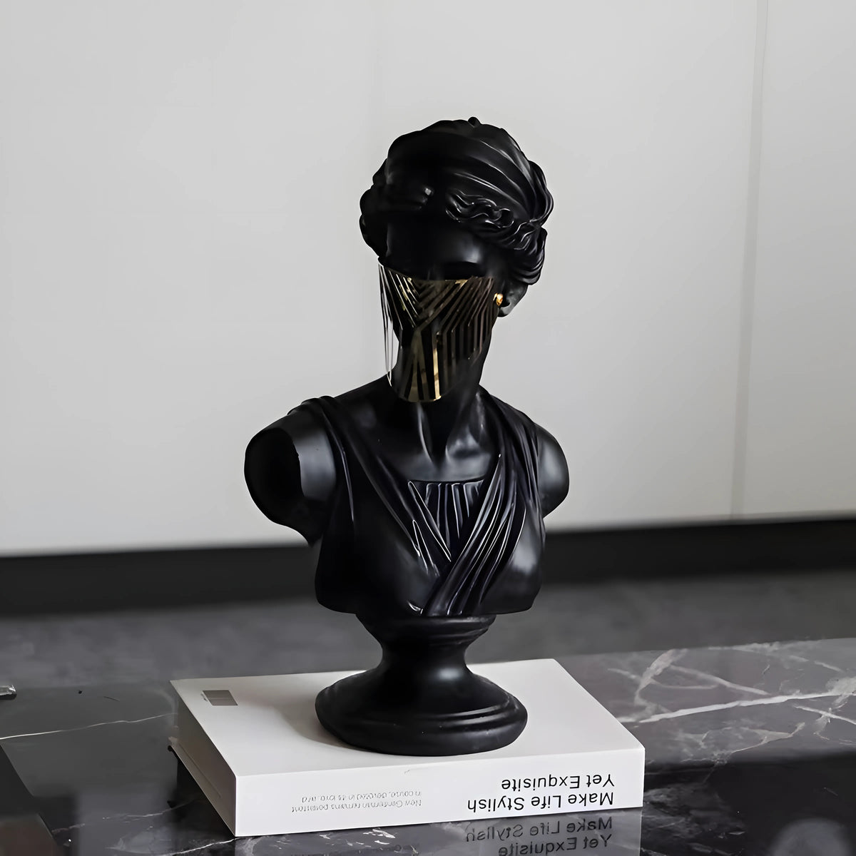 Black bust sculpture on a white platform with a neutral background