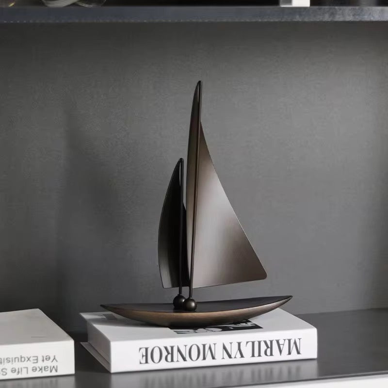 Decorative sailboat sculpture on a book with a gray background