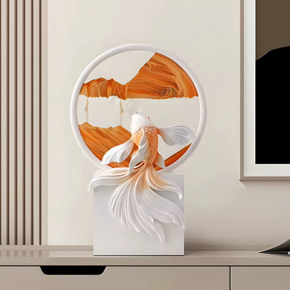 A decorative sculpture of a white and orange koi fish in front of a circular frame containing an abstract orange and white landscape, displayed on a white pedestal in a modern interior setting.