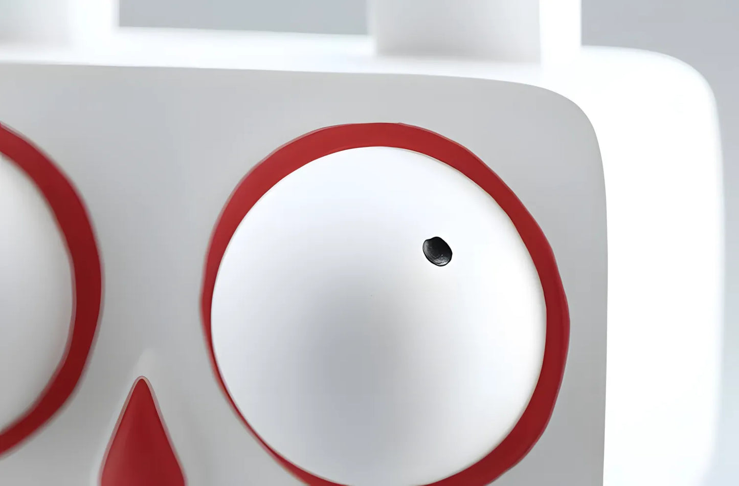 Detailed close up view of the large round white eye with a bold red rim and black pupil on the bunny sculpture