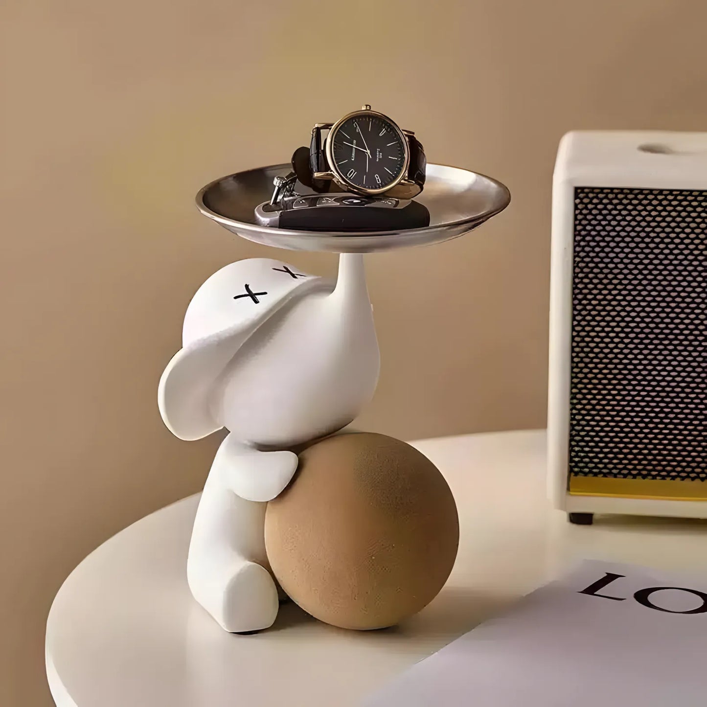 Stylish matte white elephant valet tray organizer holding a wrist watch on a bedside table nightstand