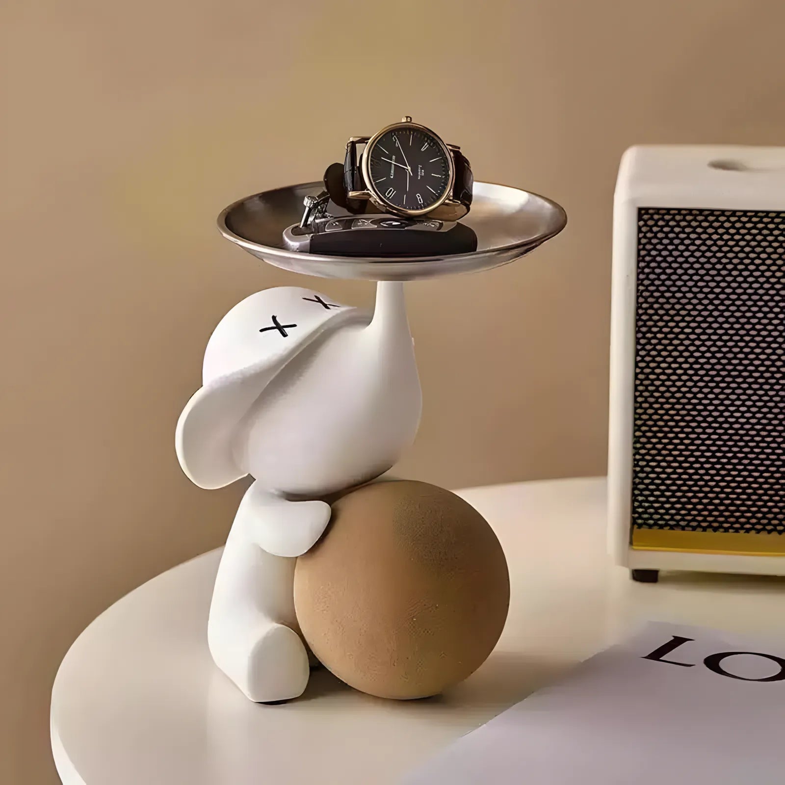 Stylish matte white elephant valet tray organizer holding a wrist watch on a bedside table nightstand