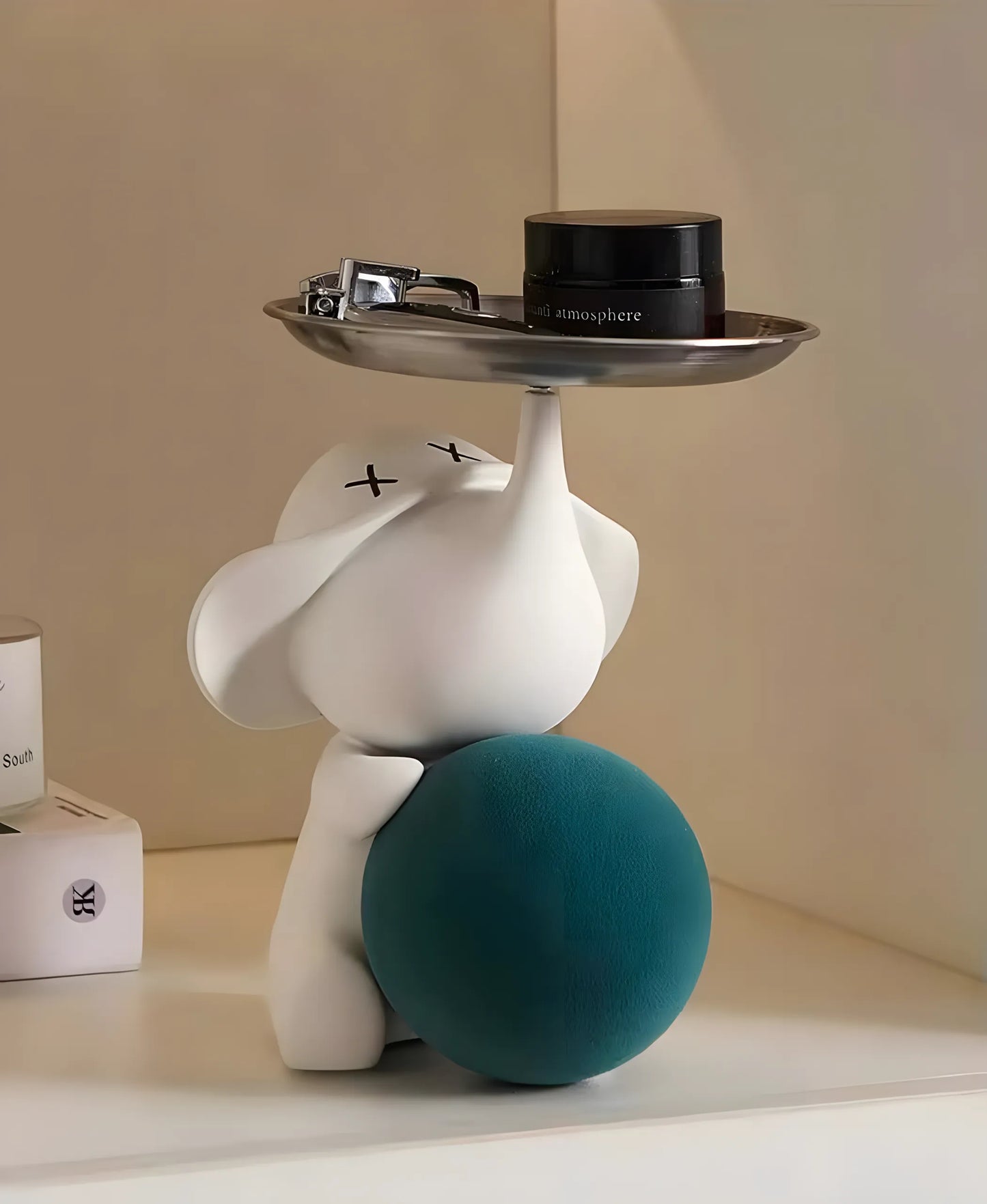 Modern matte white pop art elephant sculpture holding a stainless steel tray filled with cosmetics on a nightstand