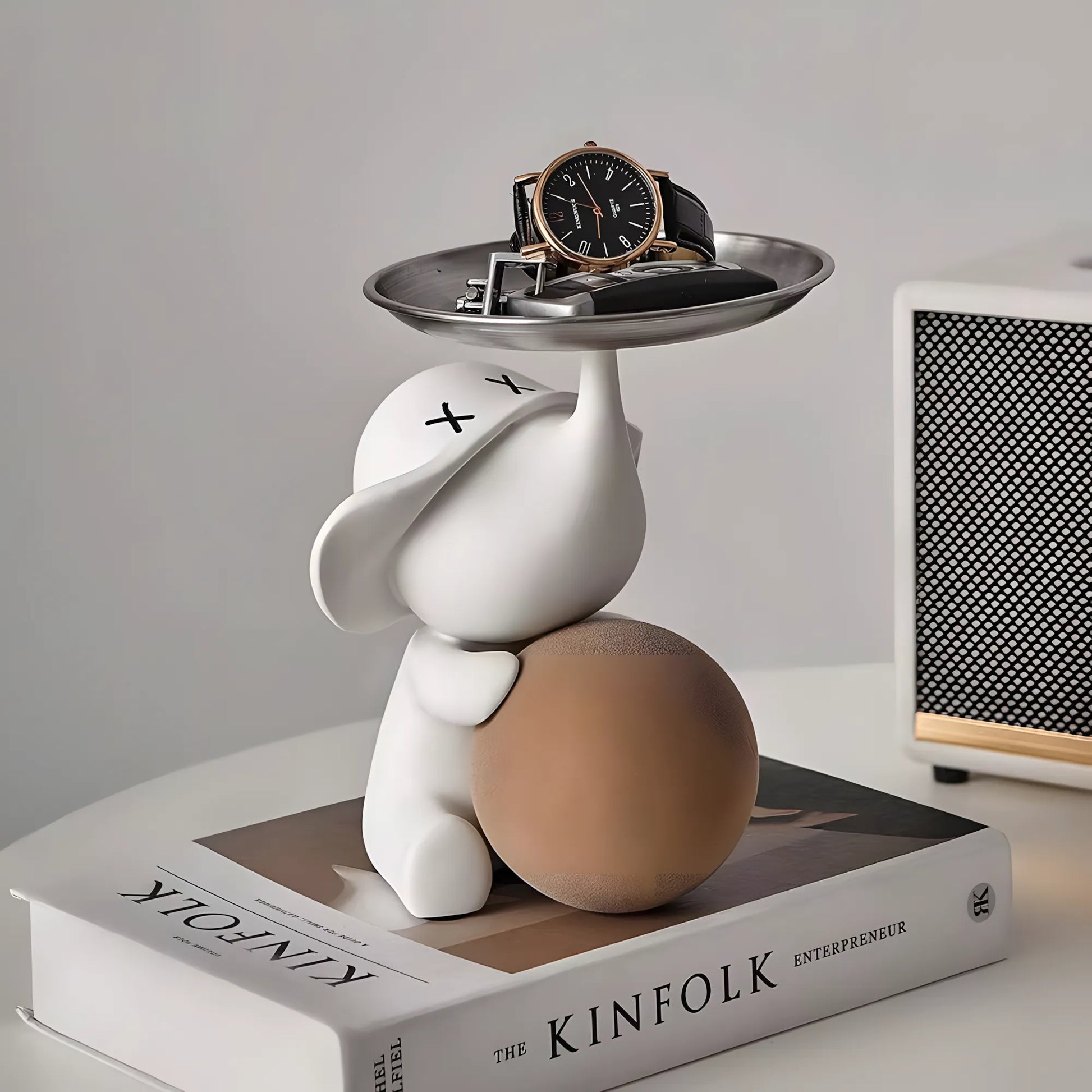Modern matte white pop art elephant key tray sculpture with a black watch and keys on top of a Kinfolk book