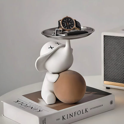 Modern matte white pop art elephant key tray sculpture with a black watch and keys on top of a Kinfolk book