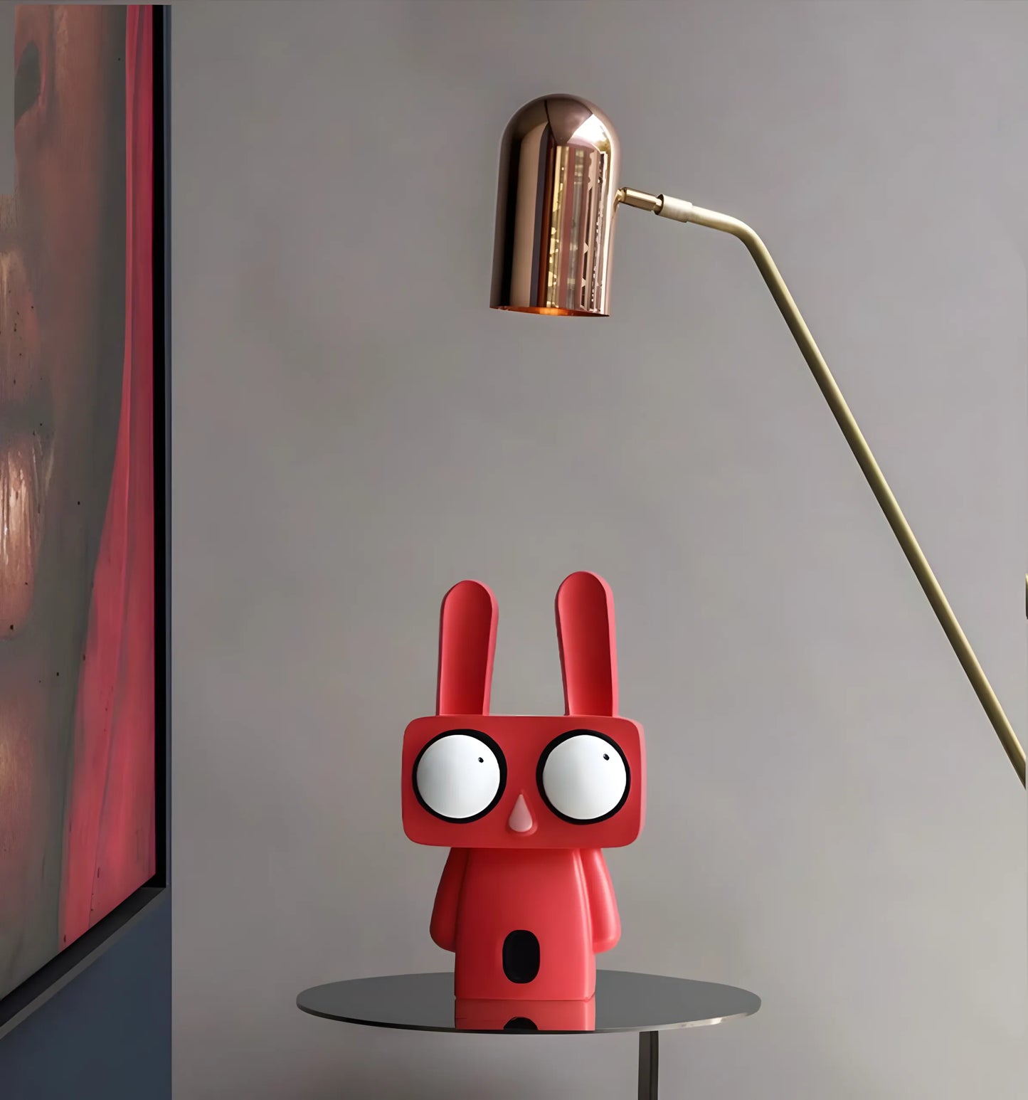 Two pop art rabbit figurines in coral red and minimalist white standing on separate white cylindrical display pedestals