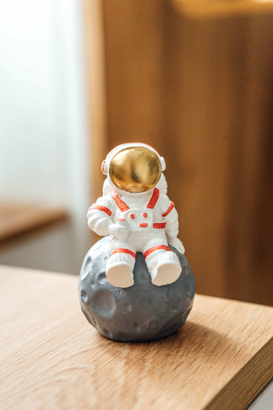 Astronaut figurine. Figurine for the interior astronaut sitting on the moon red